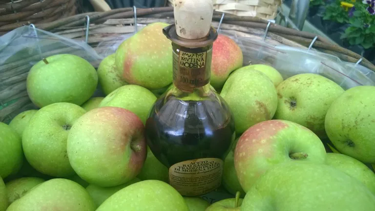Balsamic vinegar bottle among apples in Modena.