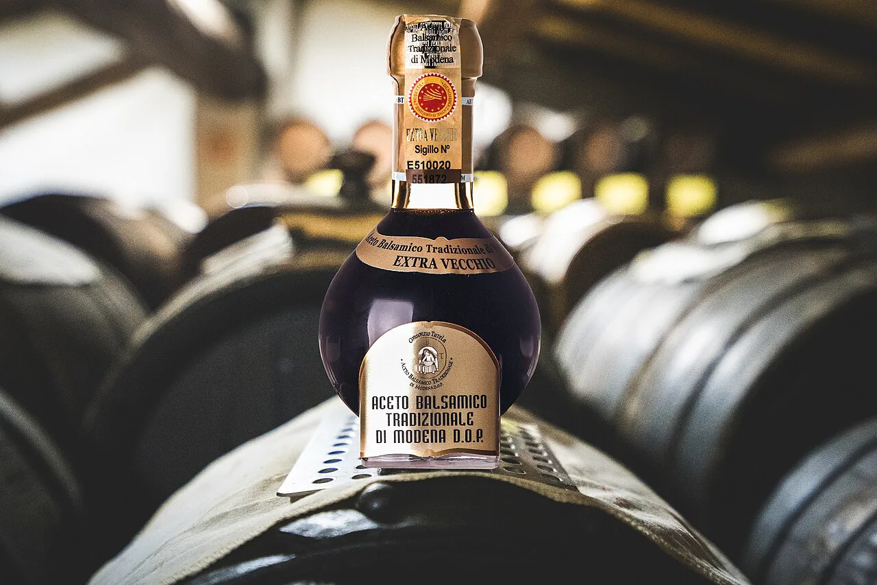 Bottle of traditional balsamic vinegar ageing on barrels in Modena.