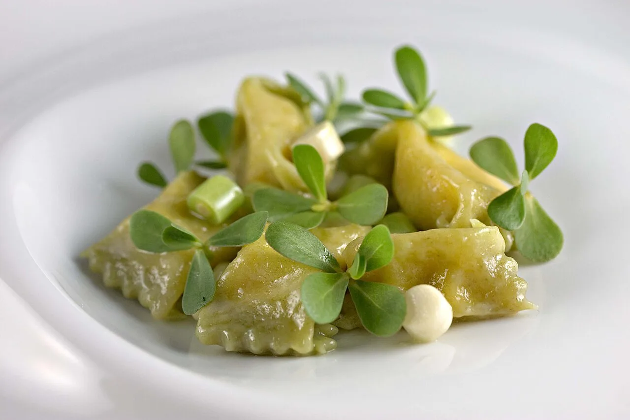 Plated agnolotti with fresh herbs.