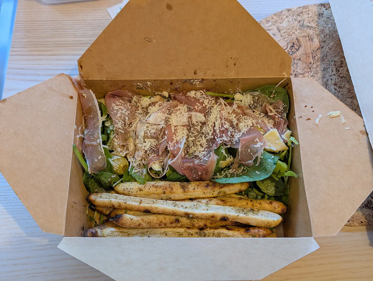 Takeaway box of salad and cured meat in Parma.