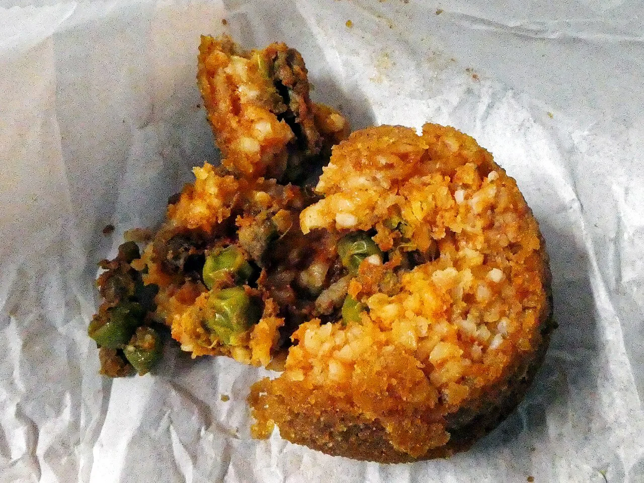 A cut arancino showing the ragù and pea filling.