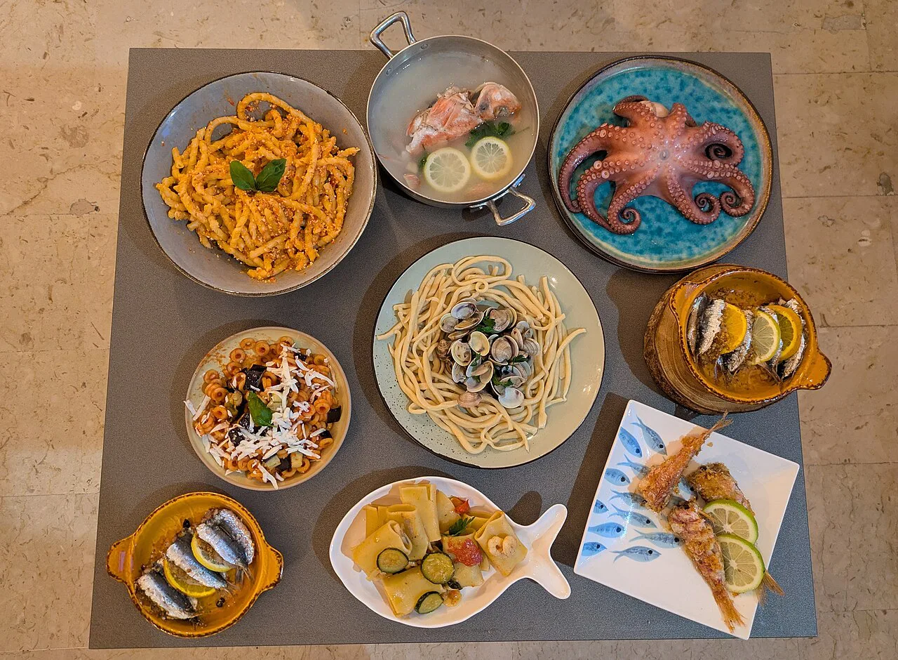 Pasta and fish dishes on a table in Catania.