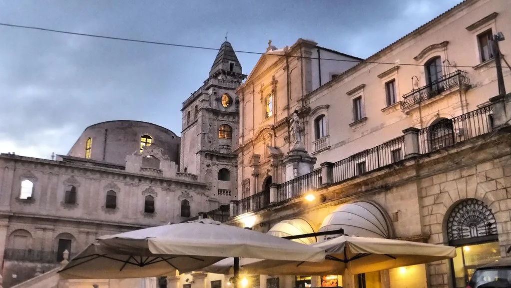 Noto cathedral with café umbrellas in the evening.