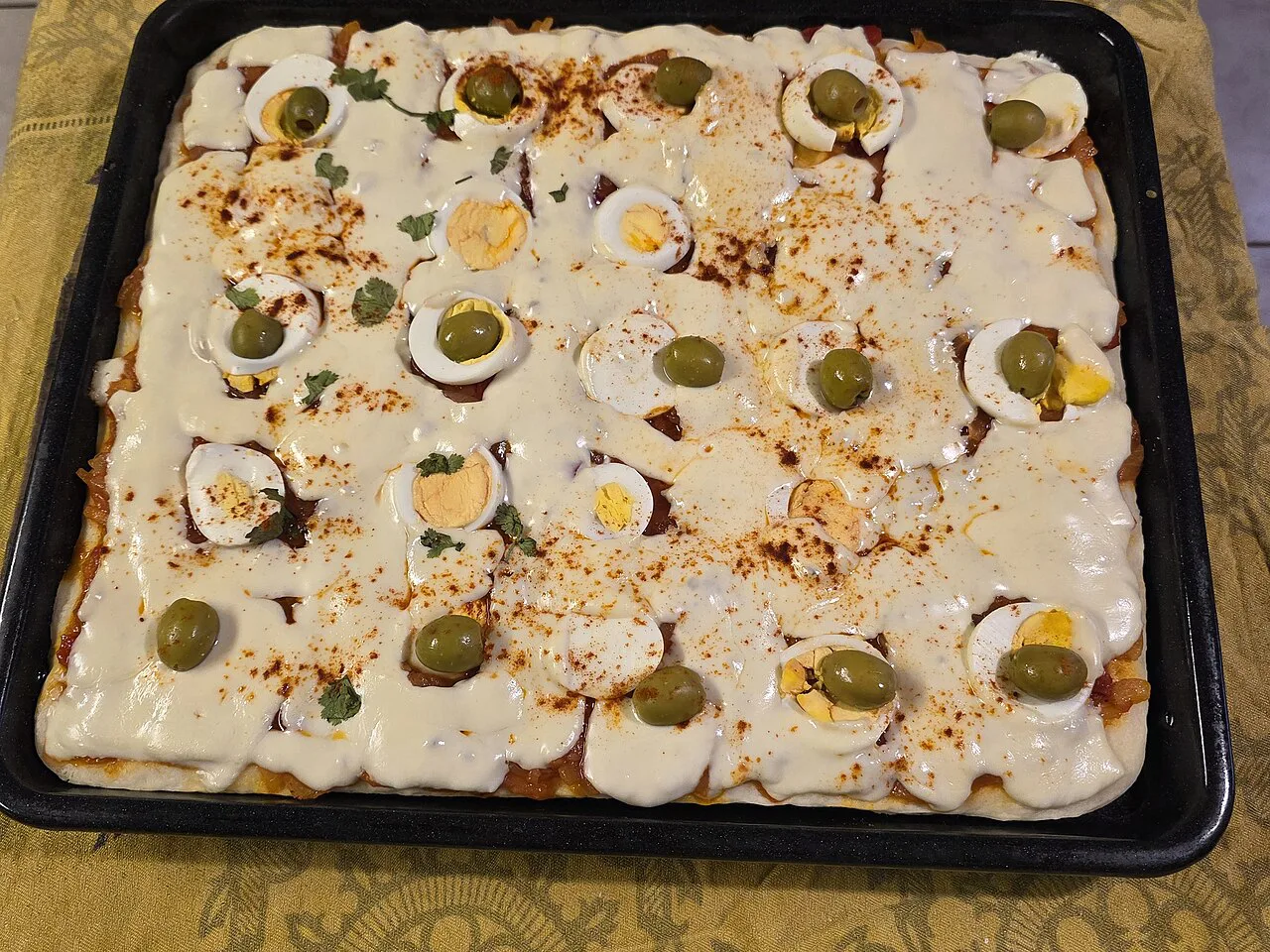 A rectangular pizza topped with cheese and olives.