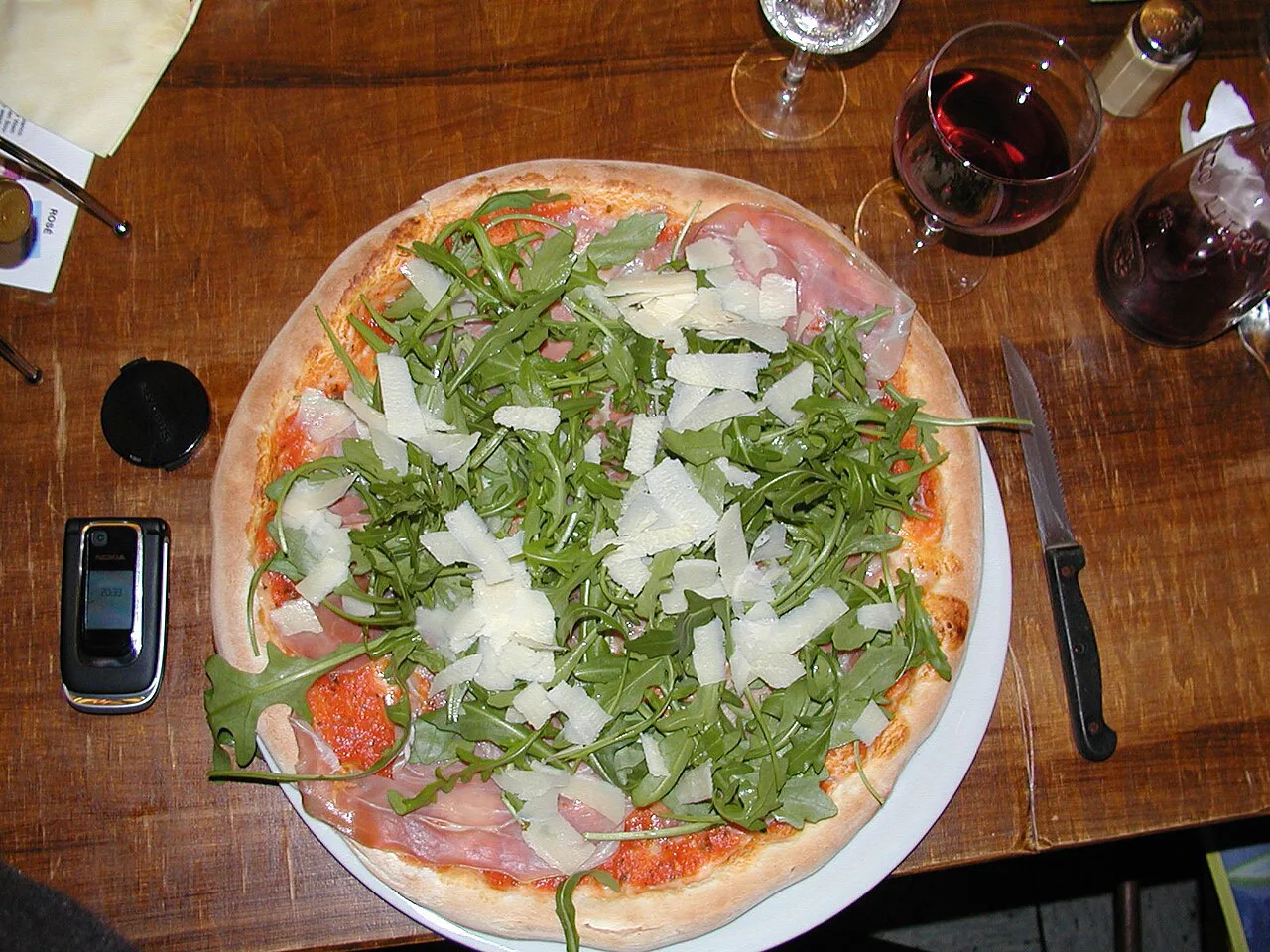 Pizza topped with rocket on a restaurant table.