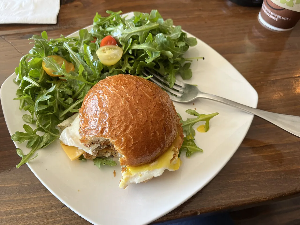 A brioche bun breakfast sandwich with salad.