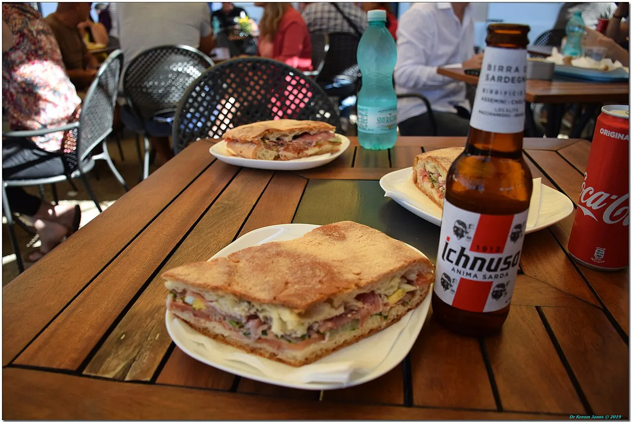 Sandwich and a drink at an Alghero café table.