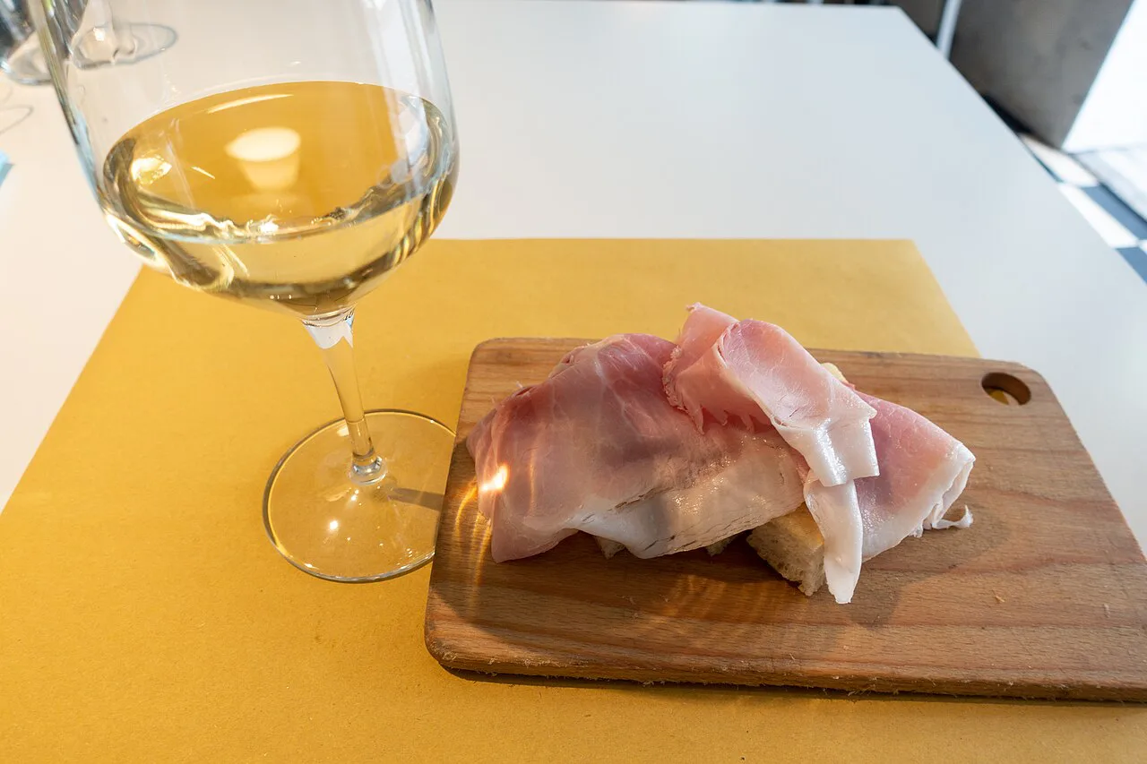 Glass of white wine with cured ham in Genoa.