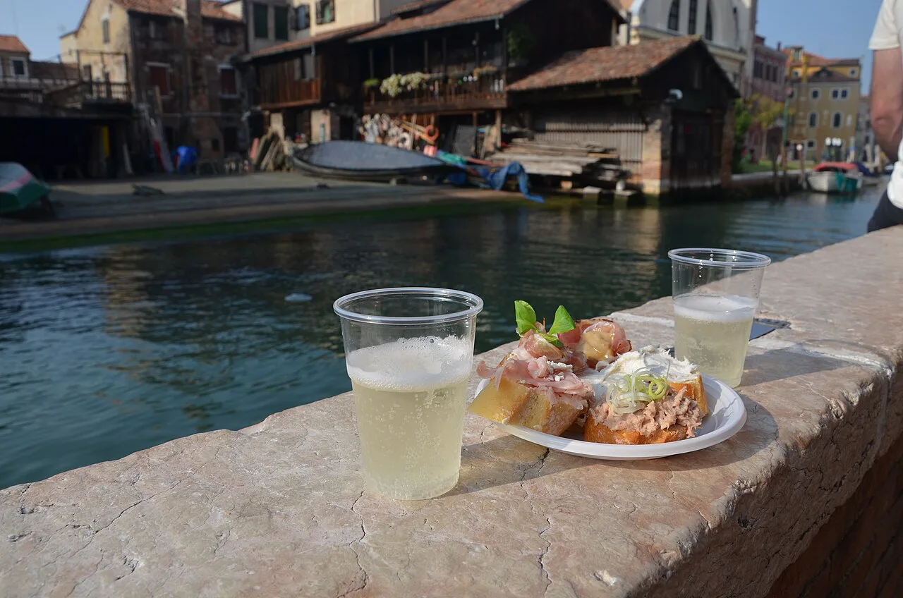 Prosecco and cicchetti beside a Venetian canal.