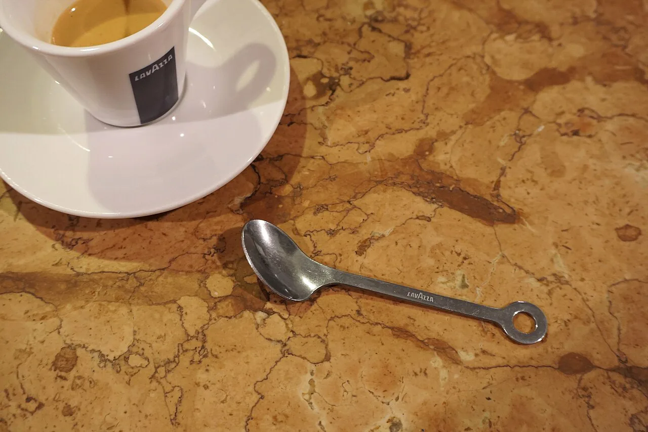 An espresso cup with a spoon on a marble table.