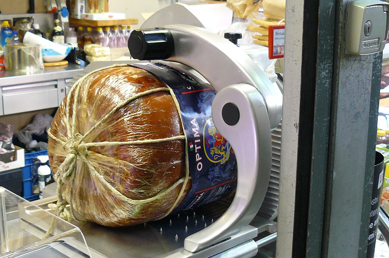 Cured meat on a slicer in an Italian food shop.