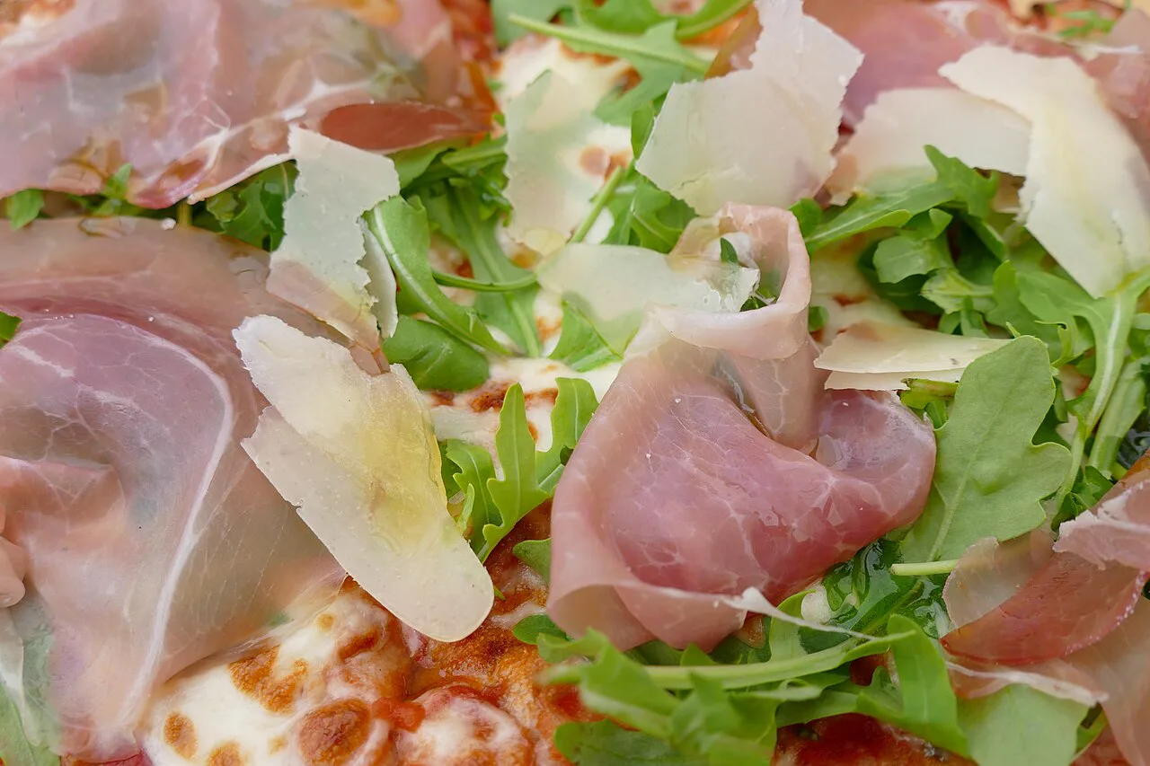 Pizza topped with rocket and cured ham.