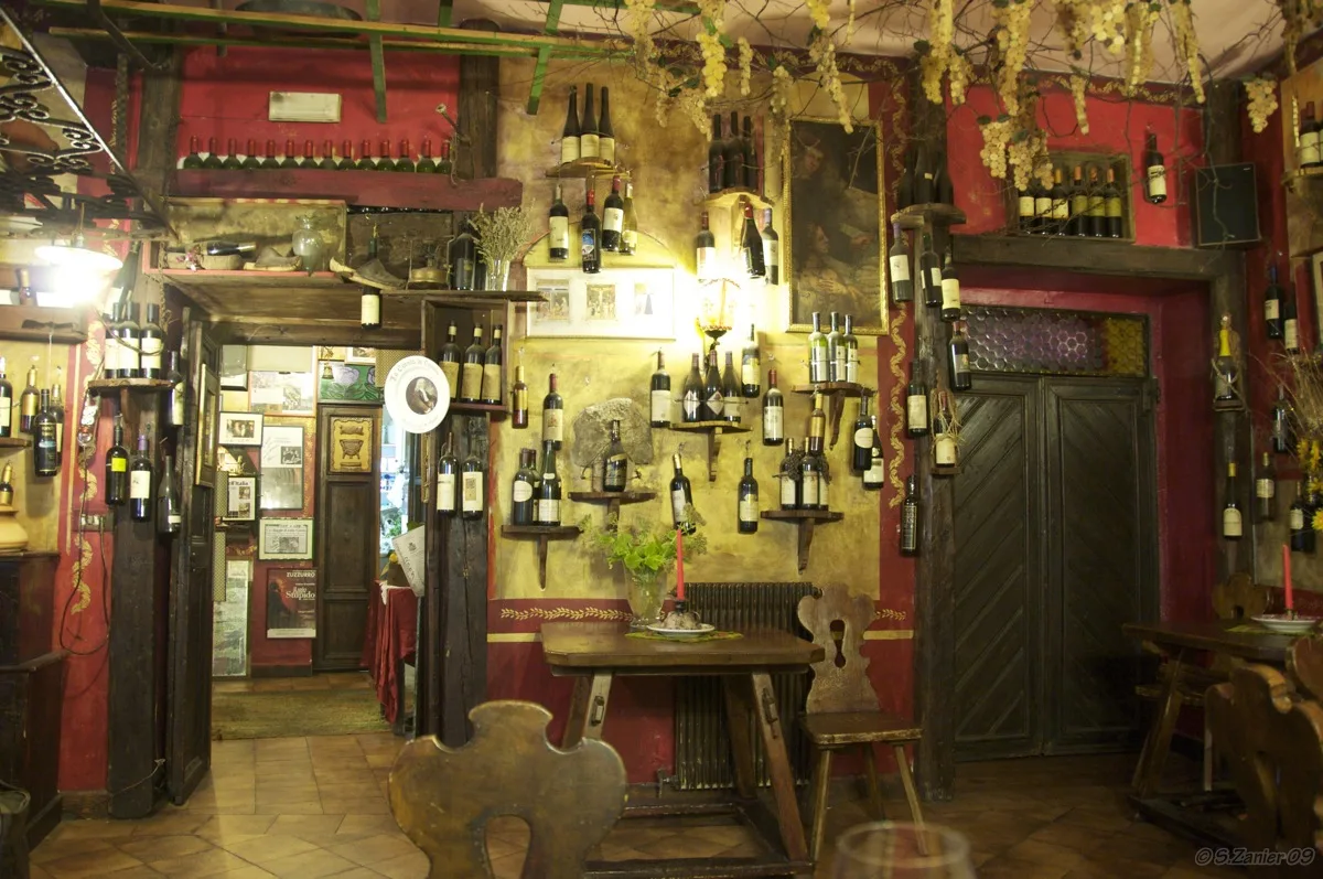 Trattoria interior with wine bottles on the walls.