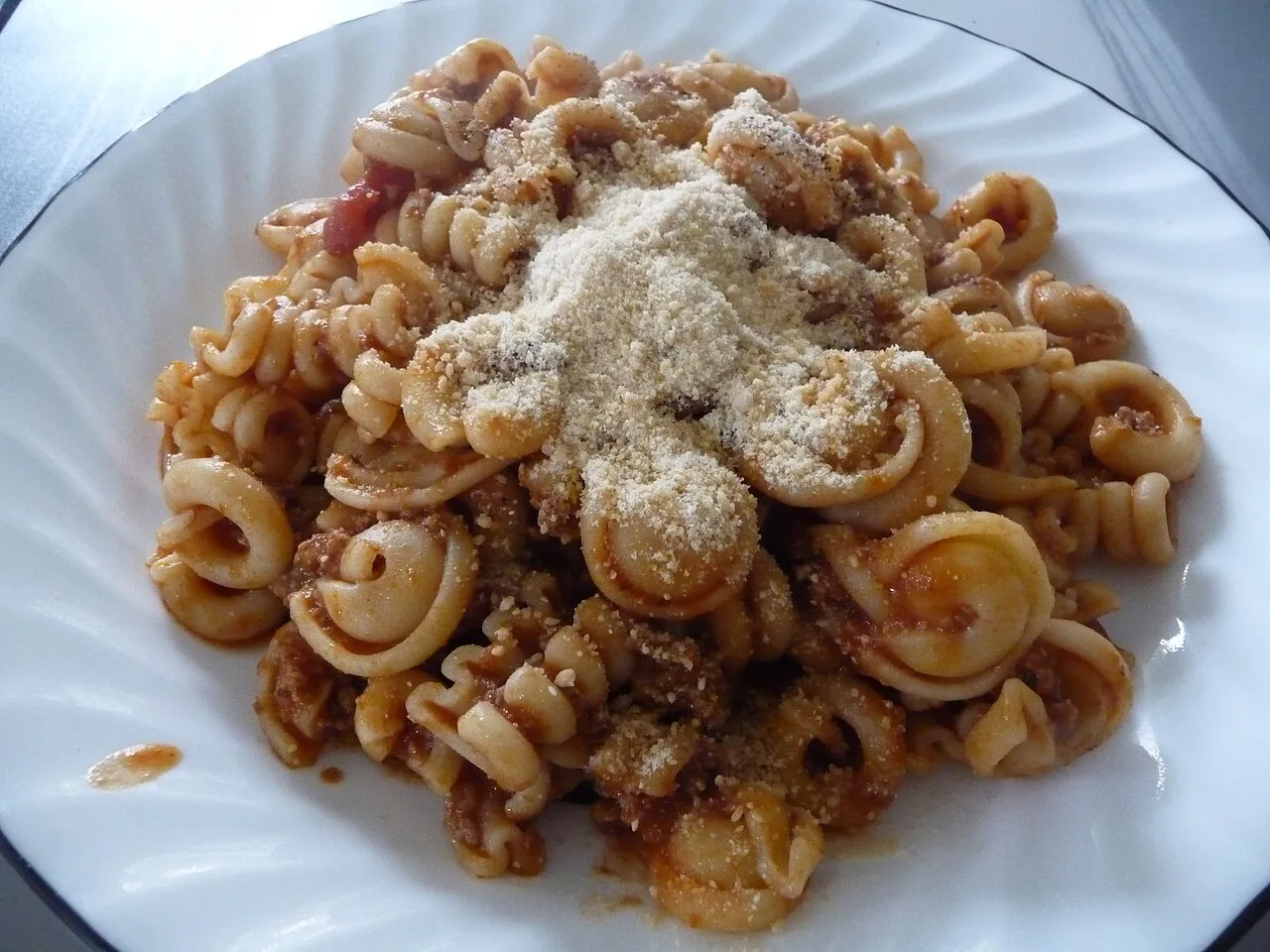 A plate of short pasta with sauce and cheese.