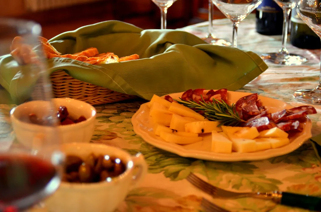 Cheese, olives, bread and wine on an Italian lunch table.