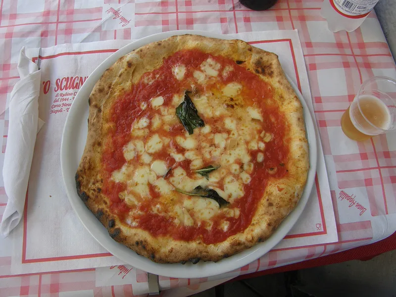 A pizza margherita on a checked cloth.