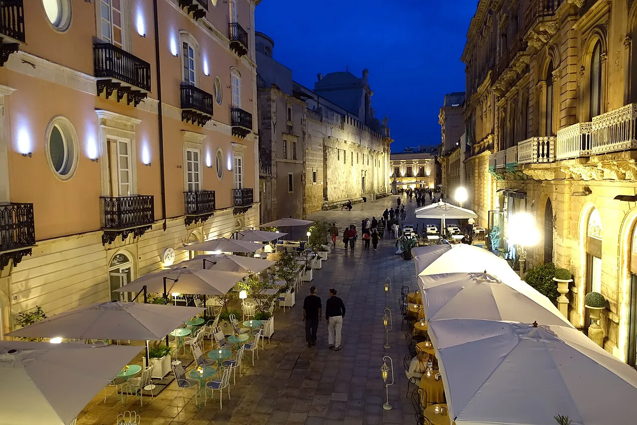 Ortigia street with cafe tables at night.
