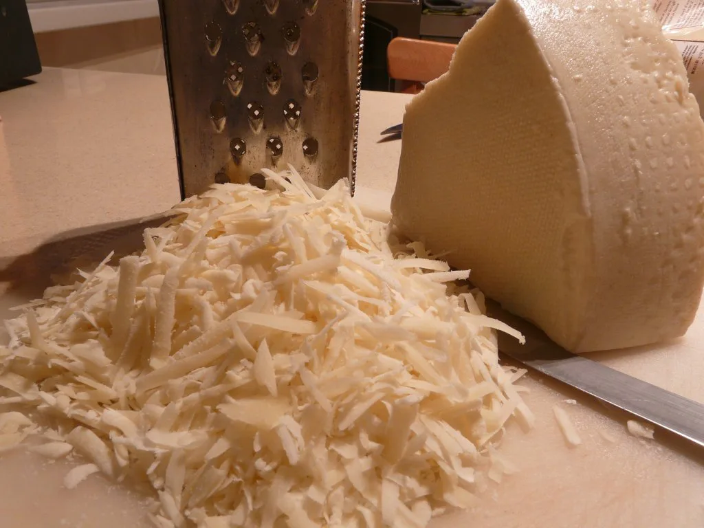 Grated pecorino beside a wedge of the cheese.