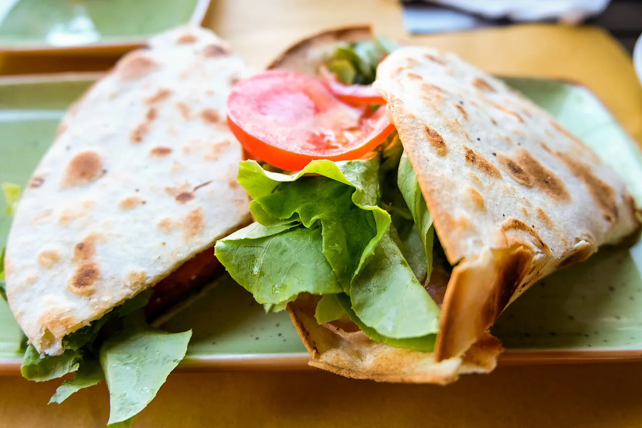 A piadina sandwich with salad and tomato.