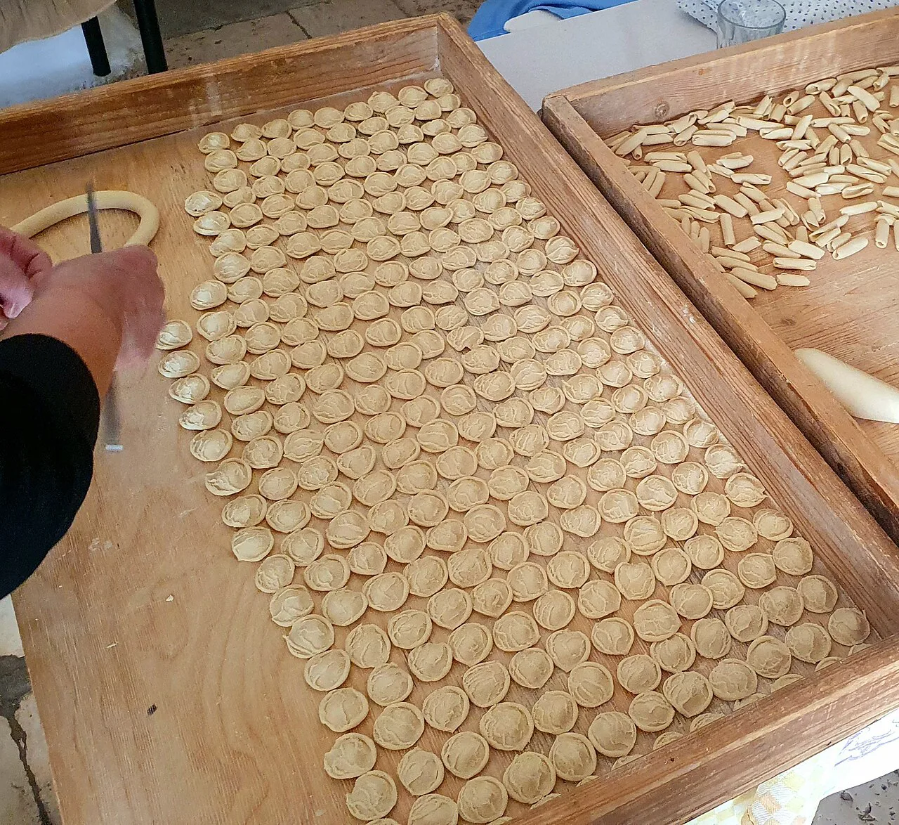 Orecchiette drying on a wooden tray.