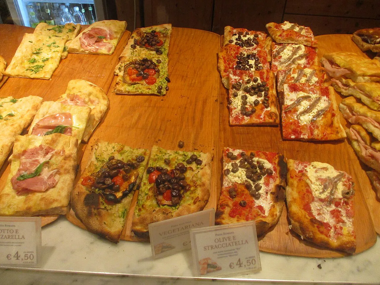 Slices of Roman pizza at a bakery counter.