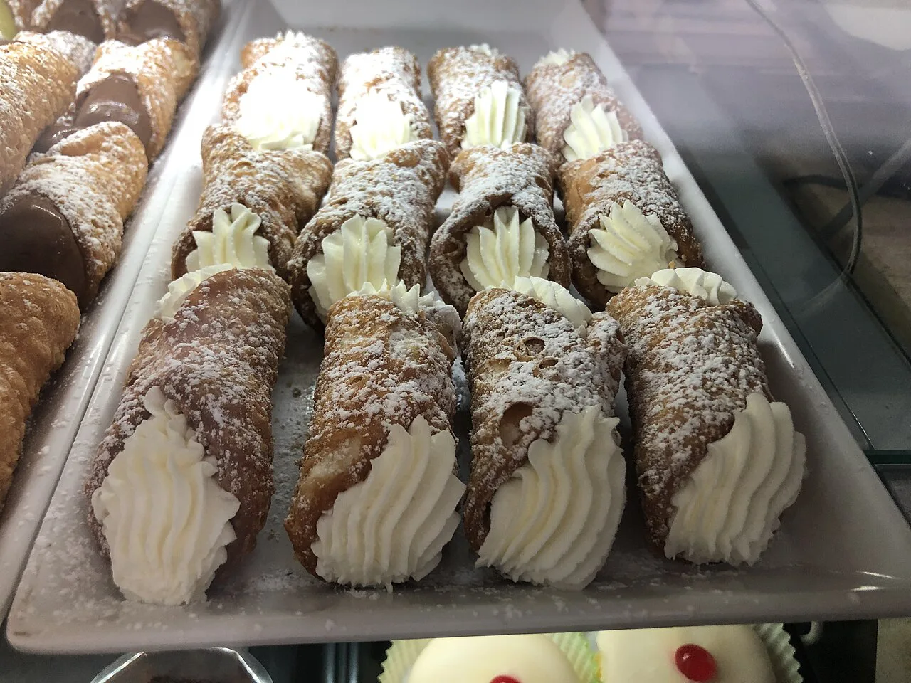 Cannoli filled with cream in a display case.