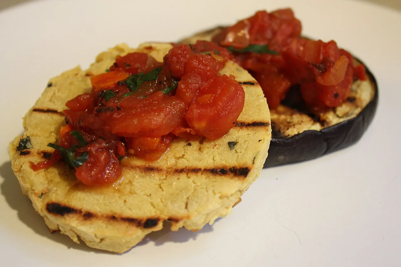 Grilled panelle topped with tomato, with aubergine.