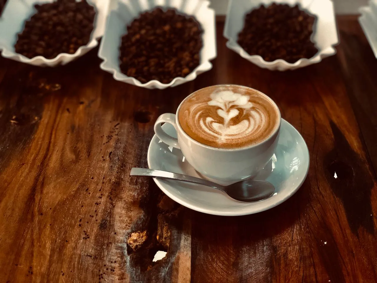 A cappuccino with latte art beside coffee beans.